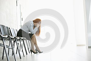 Side view of exhausted businesswoman sitting on chair in office