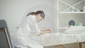 Side view of exhausted Caucasian woman sitting in hospital ward leaning head on hand. Portrait of tired female doctor at