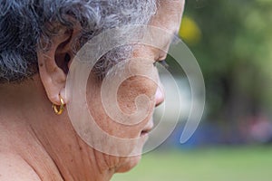 Side view of the face of a senior woman wearing a golden earring. Concept of aged people and healthcare