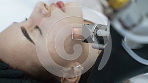 Side view face of young woman on laser facial peeling procedure, slow motion