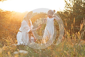 Side view of family wearing white dresses, standing near pines in forest illumined by sunset in summer. Relationship.