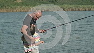 Side view of father with his kid fishing together while standing on river bank