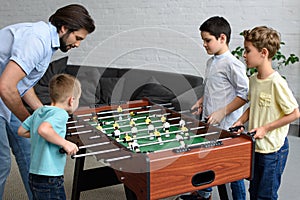 side view of father and little sons playing table football together