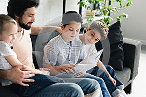 side view of father and sons reading book together