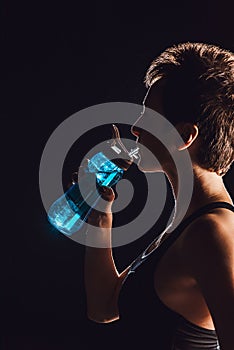 side view of female athlete drinking water from sport bottle black