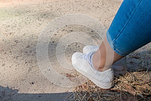 On side view at female foots on road with grass. Girl is sitting on the road. Place for text.