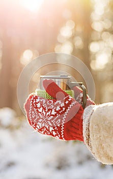 Side view of female hand holding hot cup of coffee in winter