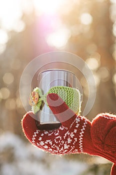 Side view of female hand holding hot cup of coffee in winter