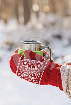 Side view of female hand holding hot cup of coffee in winter