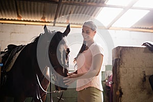 Side view of female jockey stroking horse