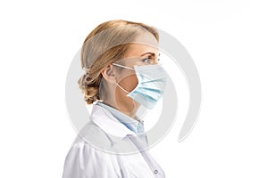 side view of female middle aged doctor in medical mask looking away