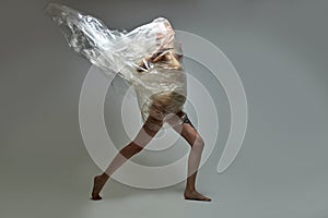 Side view on female in a plastic bag, breaking free from plastic trash