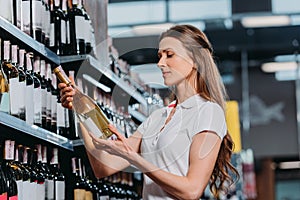 side view of female shop assistant with bottle of wine photo