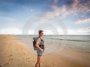 Side view of a female traveler with a backpack standing at Morro Jable Beach Fuerteventura - copy space