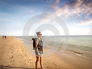 Side view of a female traveler with a backpack standing at Morro Jable Beach Fuerteventura - copy space