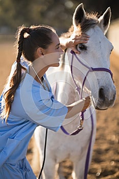 Side view of female vet checking horse