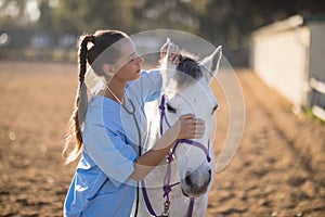 Side view of female vet checking horse ears