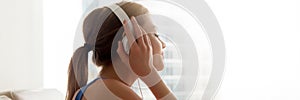 Side view female wearing headphones enjoy favorite music at home