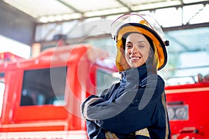 Side view of fireman or firefighter woman with protective clothes stand with confidence action and smile in front of fire truck.