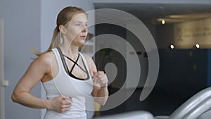 Side view of fit lady cardio training and in a gym. Woman running on treadmill.