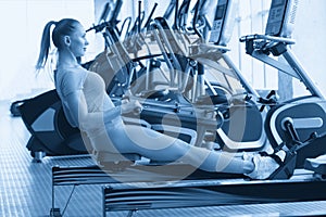 Side view of fit young women using rowing machine in health club