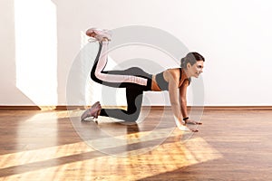 Side view of fitness woman doing one legged plank pose, training buttocks muscle flexibility.