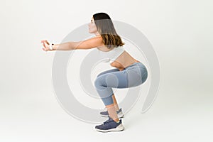 Side view of a fitness woman squatting