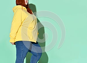 Side view of a flirtatious curvy young woman putting one foot on toe in front of other. Full length shot isolated on blue