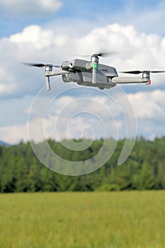 Side view of a flying modern drone on yellow corn field