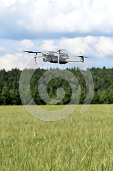 Side view of a flying modern UAV drone on yellow corn field