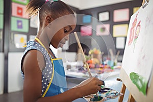 Side view of focused girl painting on canvas