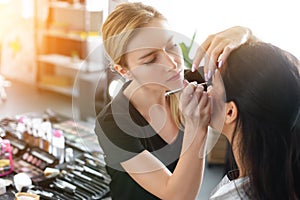 side view of focused makeup artist applying eye shadows