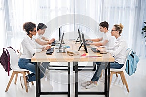 side view of four young multicultural students studying