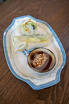 Side view of fresh Vietnamese spring rolls, cold, with dipping sauce with peanuts