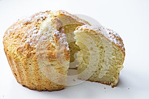 Side view of a freshly baked cupcake with a cut piece on a white background.