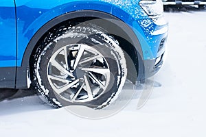 Side view of the front of a blue car on a snowy road during the winter season