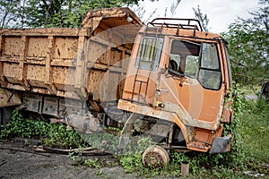 Side view of front part from a brown broken brown old truck that has been badly damaged abandoned in the middle of a park