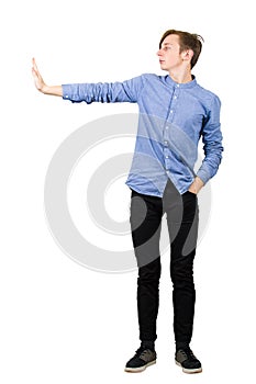 Side view full length of confident boy showing stop gesture with his palm, hand outstretched gesturing prohibition, no sign,