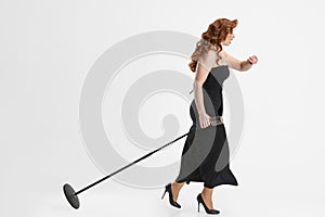 Side view full-length portrait of female singer carrying microphone and running away isolated over white background