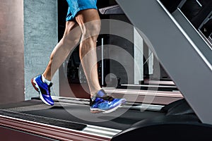 Side view full length of young man in sportswear running on treadmill at gym