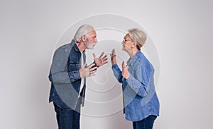 Side view of furious senior husband and wife blaming and fighting while standing on white background