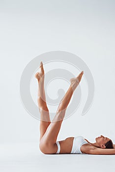 Side view of girl that lying down. Beautiful woman with slim body in underwear is in the studio