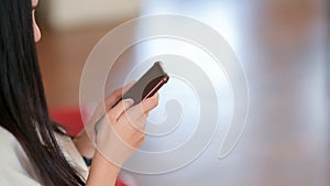 Side view of a girl using smartphone with blurred stylish living room background