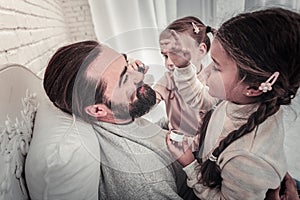 Side view of girls painting their fathers face with make up