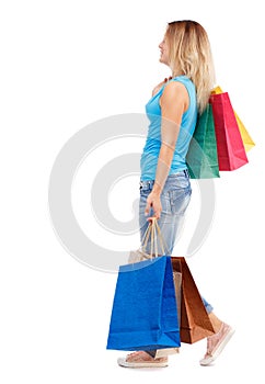 Side view of going woman with shopping bags .