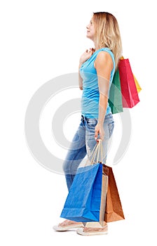 Side view of going woman with shopping bags .