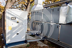 Side view of the gray commercial central air handling unit with cooling coil and big condensing unit standing outdoor on the groun