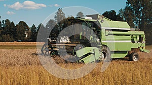 Side view of a Green Modern Combine Harvester In A Wheat Field Ready To Harvest