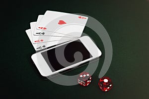 Side view of a green poker table with a smartphone, cards and dices. Gambling app addiction