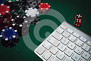 Side view of a green poker table with some poker cards on a keyboard. Betting on-line concept